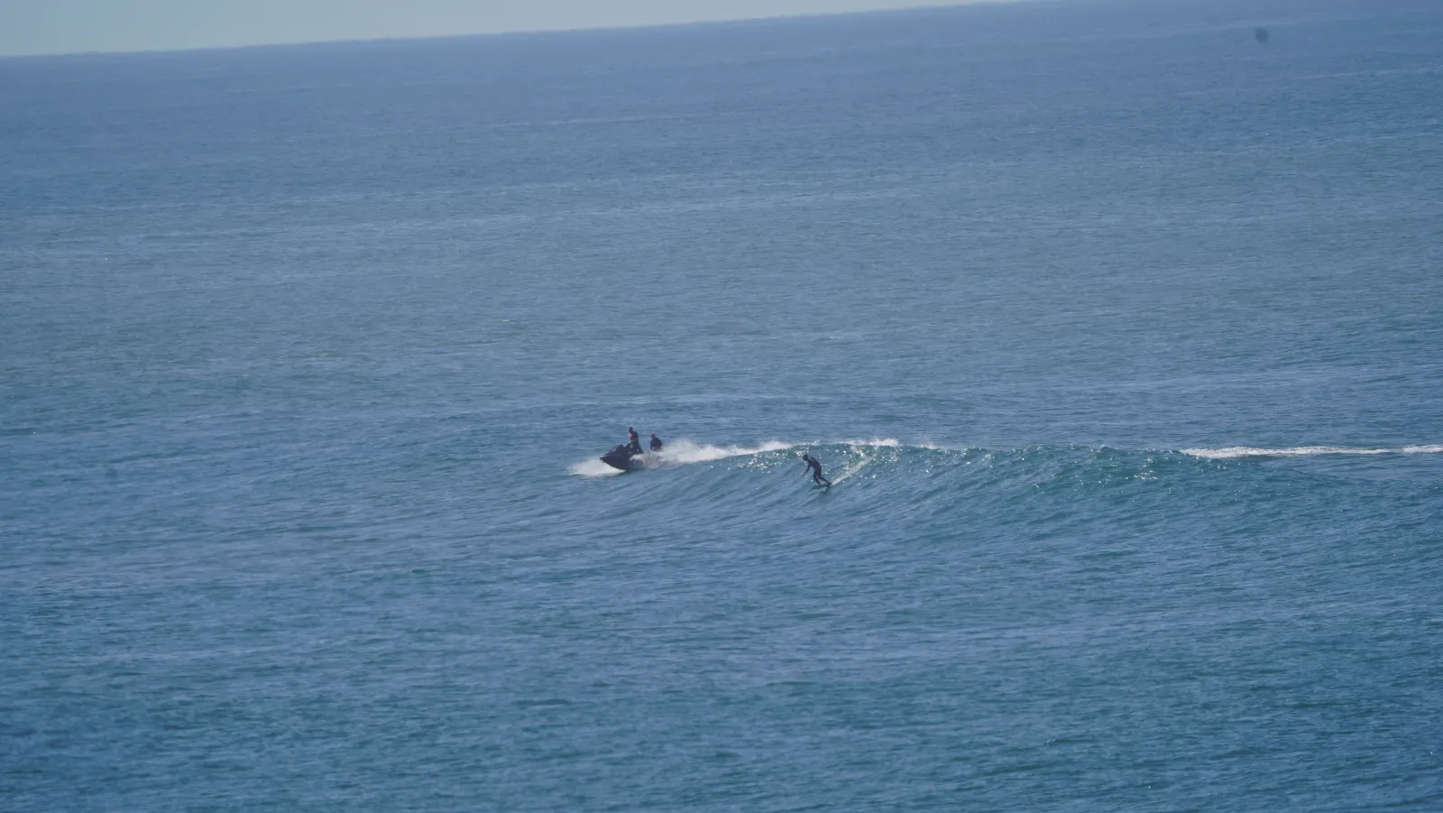 Un towfoiler su un'onda, con il jetski subito dietro