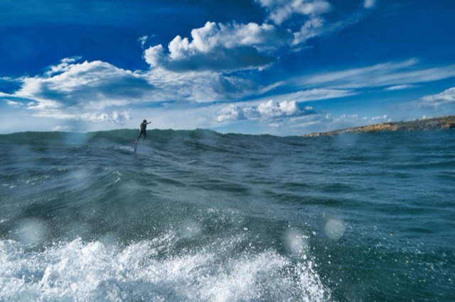 On the wave, coastline behind