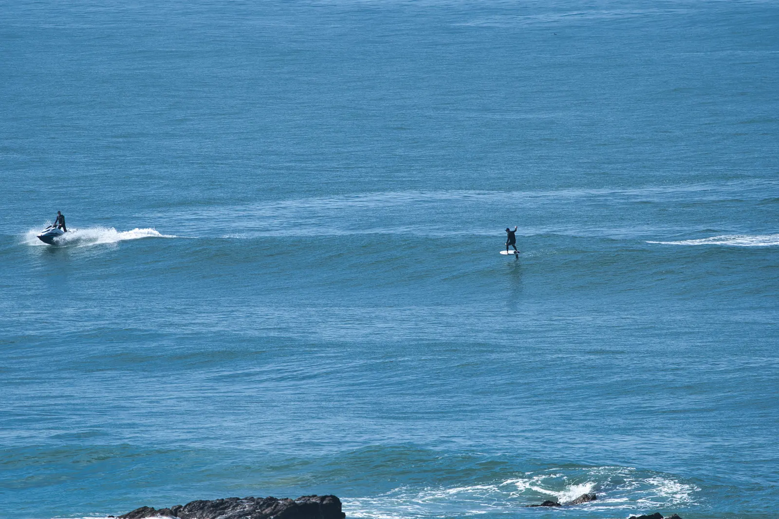 Foiler celebrating a wave with both arms up while the ski circles back